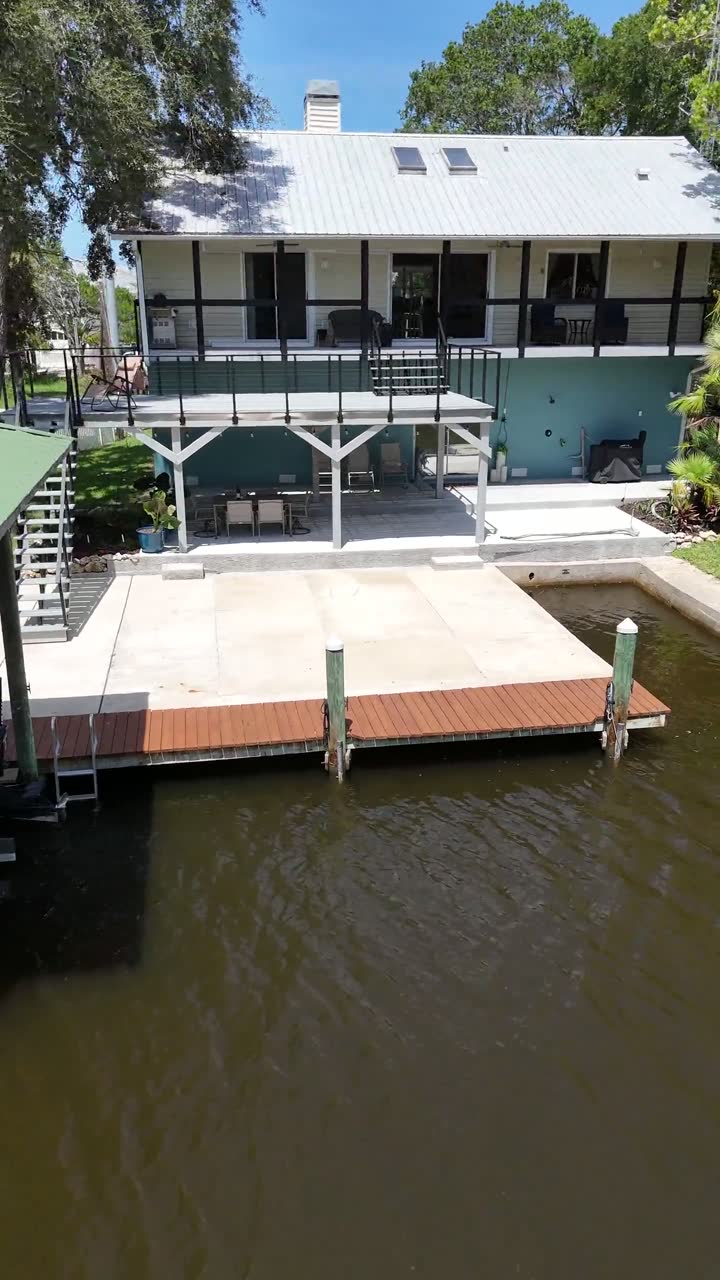 The private dock, the concrete deck at the water's edge and the back of the riverhouse on Mason Creek